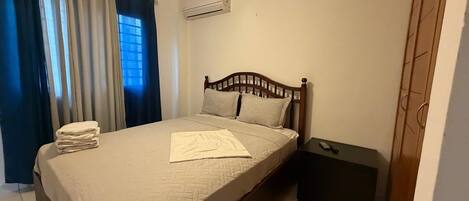 Una camera da letto con un letto, un comodino, una ventola a soffitto e un condizionatore d'aria.
