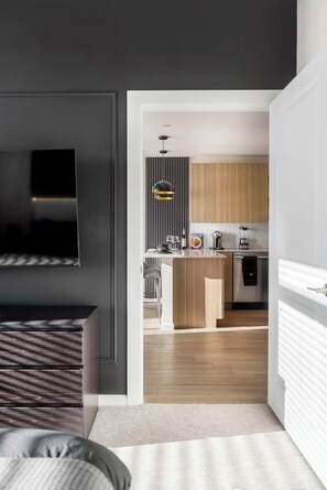 A modern kitchen with wooden cabinets, a central island, and a built-in oven. - The Dominic - 1BR Condo, King Bed, Pool, Gym (Orlando)