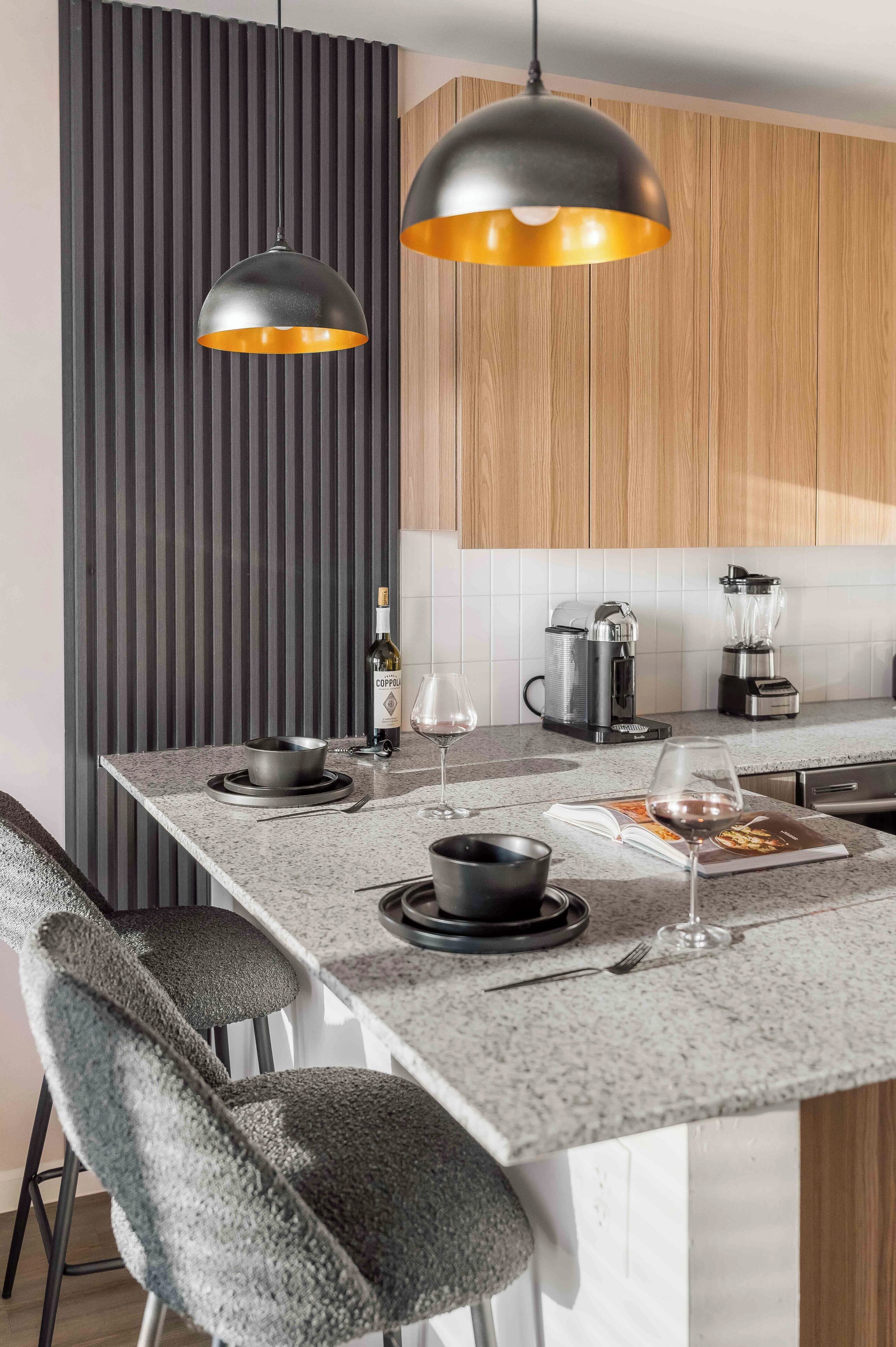 Una cocina moderna con una isla central, iluminación colgante y un rascador para gatos.