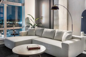A modern living room with a sectional sofa, a round coffee table, and a floor lamp. - The Dominic - 1BR Condo, King Bed, Pool, Gym (Orlando)
