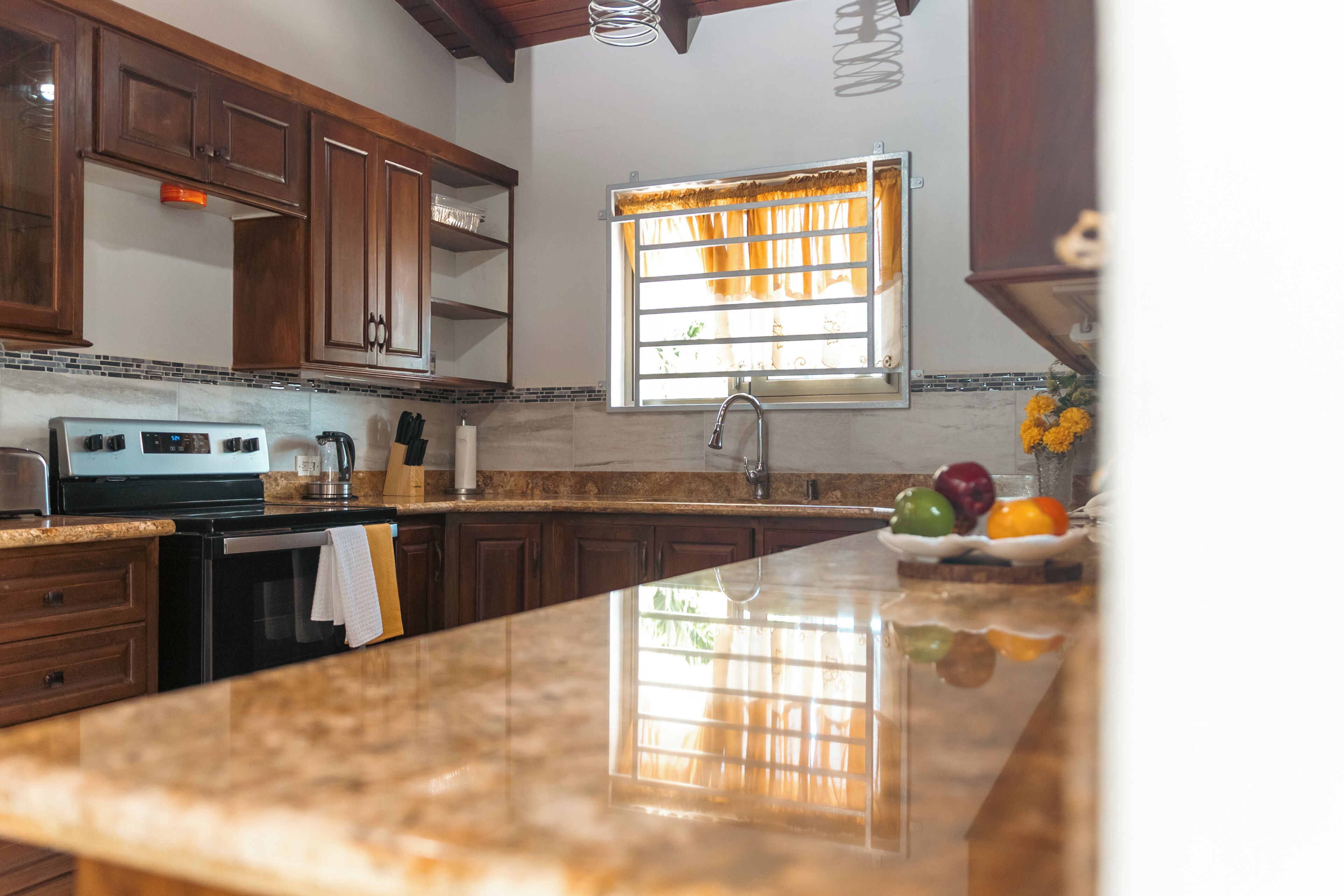 Una cocina con armarios de madera, una estufa de acero inoxidable y una ventana con cortinas.