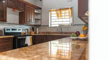 Una cocina con armarios de madera, una estufa de acero inoxidable y una ventana con cortinas.