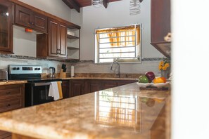 A kitchen with wooden cabinets, a stainless steel range, and a window with curtains.