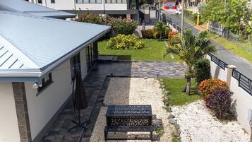 A residential property with a covered patio, a gravel pathway, and a small garden area with various plants and a bench.