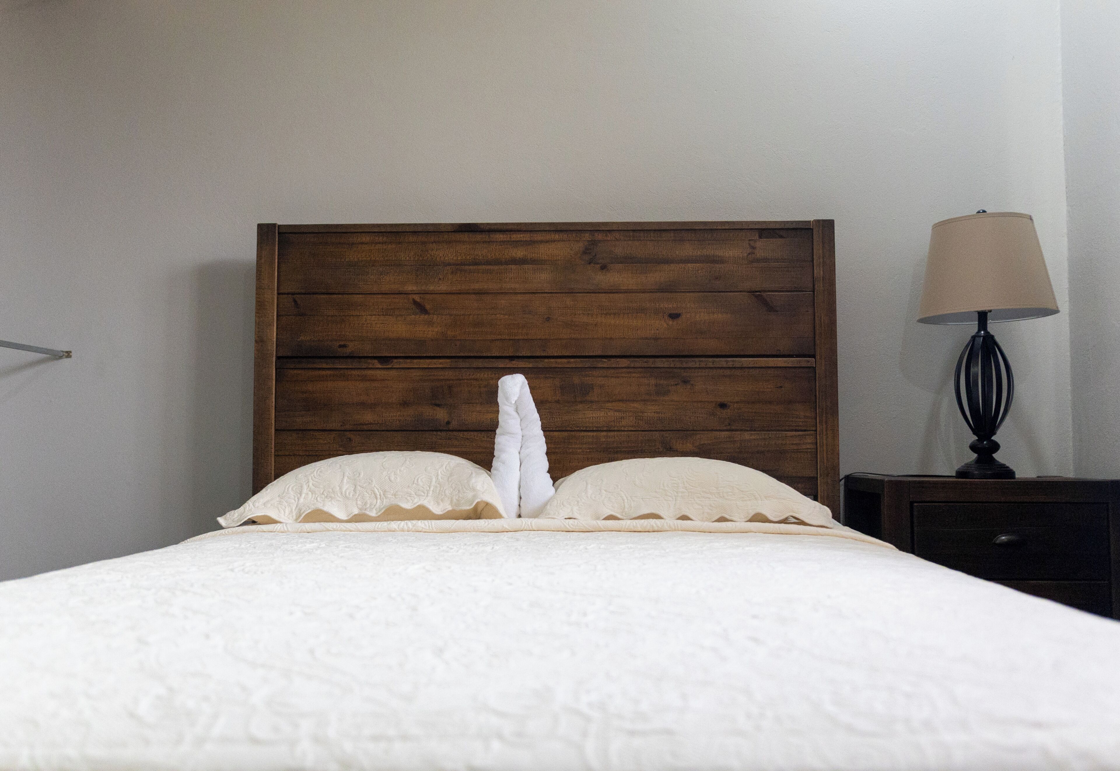 A bed with a wooden headboard, white pillows, and a white blanket.