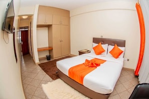 Une chambre d’hôtel comprenant un lit, une armoire, une table de chevet et un téléviseur.