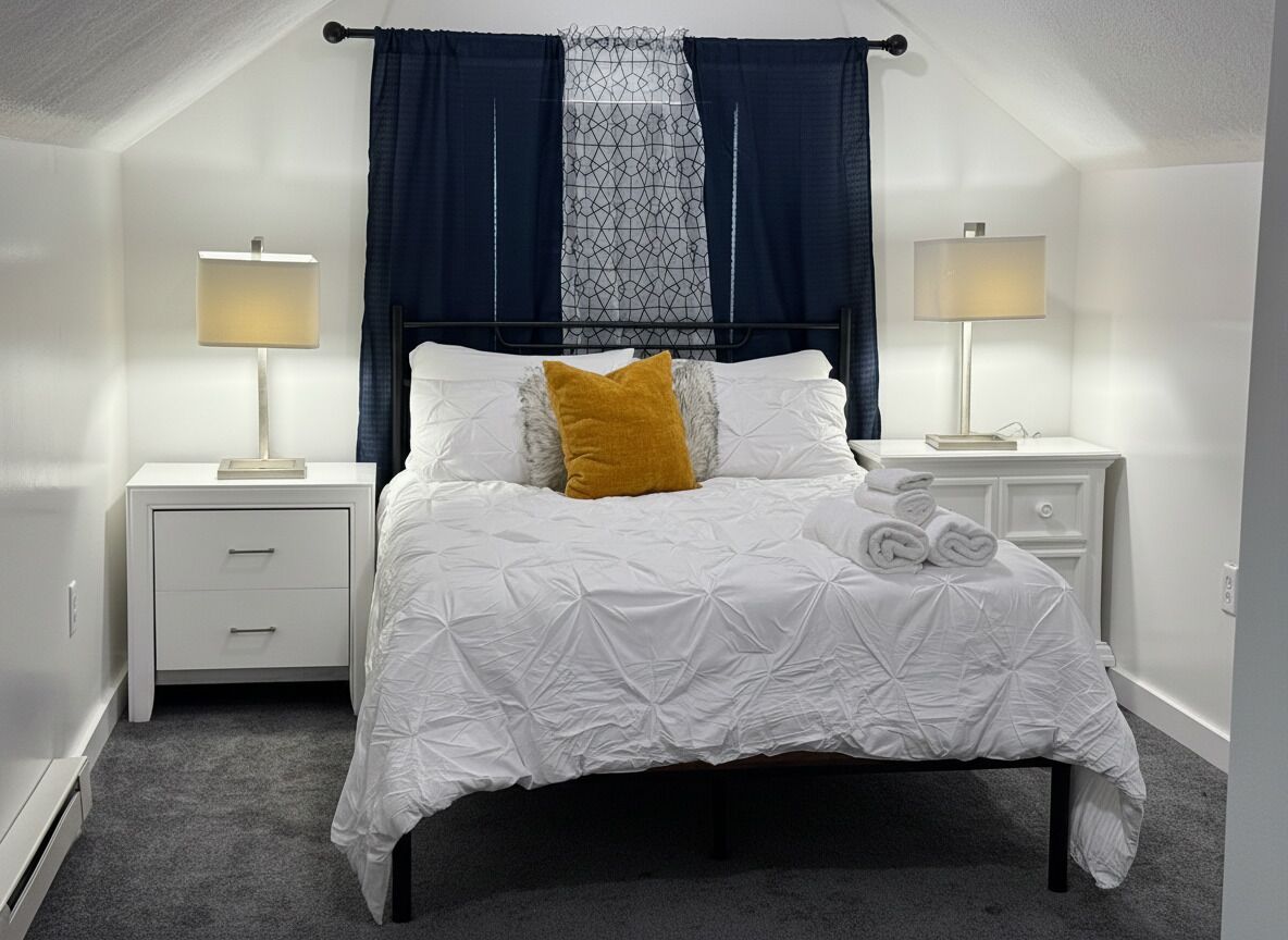 Een slaapkamer met een bed, twee nachtkastjes, een raam met gordijnen en een lamp.