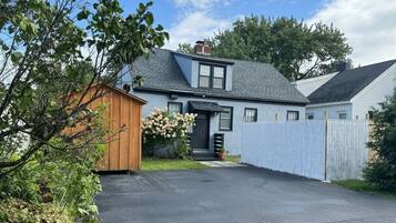 Een woonhuis met garage, houten tuinhuis en oprit.