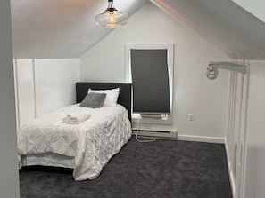 A bedroom with a bed, a window with blinds, a ceiling light, and a radiator. - Welcome to Abreu,adorable Cape Cod-style home situated in the heart of Watertown (Watertown)