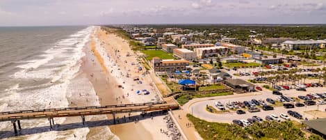 A coastal hotel with a beach view, a parking lot, and a boardwalk.
