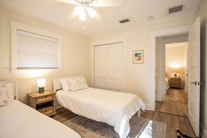A bedroom with two beds, a ceiling fan, a wardrobe, and a nightstand with a lamp. - Quiet 3-bedroom house with Bicycles and Hot Tub in laid-back St. Augustine (St. Augustine)