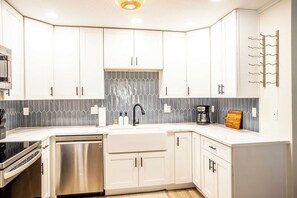 A modern kitchen with white cabinets, a stainless steel dishwasher, and a coffee maker. - Quiet 3-bedroom house with Bicycles and Hot Tub in laid-back St. Augustine (St. Augustine)