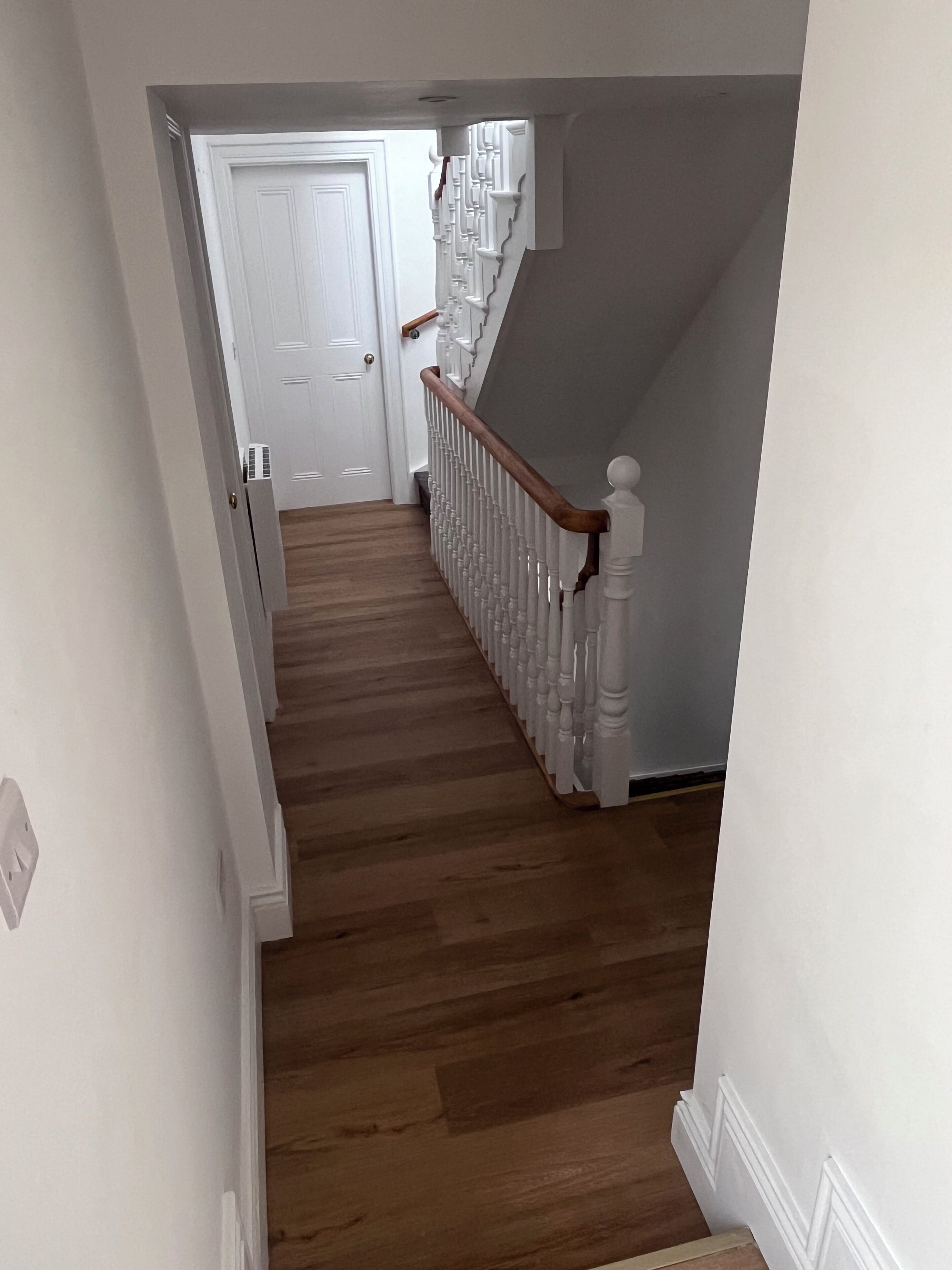 A staircase with wooden steps and white railings leading to a door.