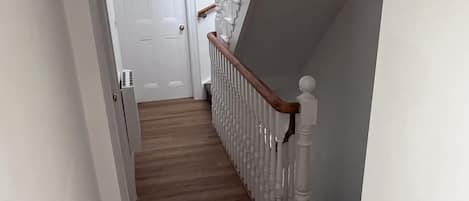 A staircase with wooden steps and white railings leading to a door.