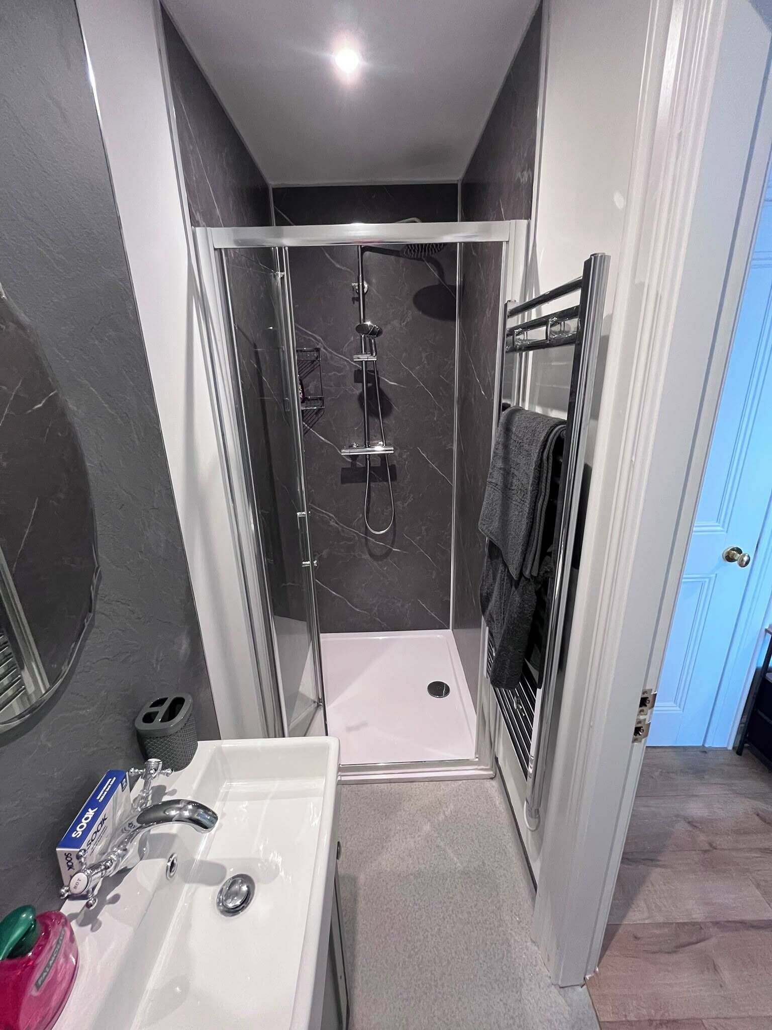 Une salle de bain moderne avec une douche à parois de verre, un lavabo blanc et un porte-serviettes.