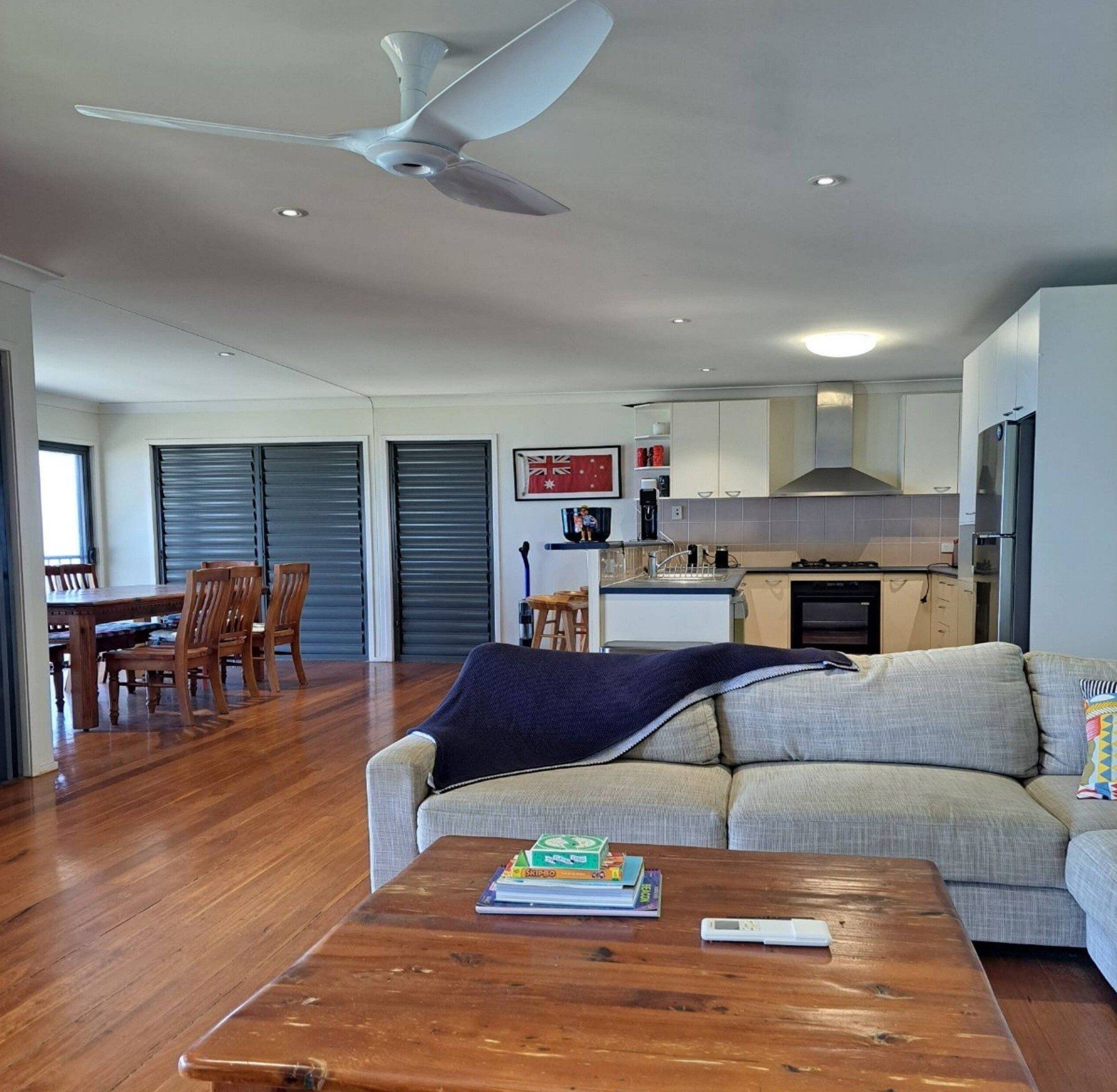A modern living room with a sofa, coffee table, and a dining area with chairs and a table.