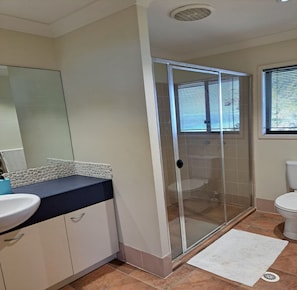 A bathroom with a glass shower enclosure, a white sink, and a toilet. - 7 Coign Tangalooma Moreton island (moreton island)