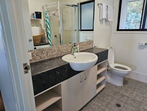 A bathroom with a white sink, a mirror, a shower, and a toilet. - 8 Coign Tangalooma Moreton island (moreton island)