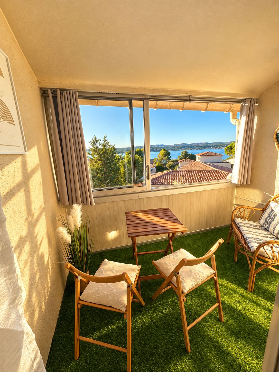 Un balcon donnant sur un lac, une table en bois, deux chaises et un petit tapis.