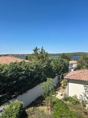 A residential area with terracotta-tiled roofs, a river, and greenery.