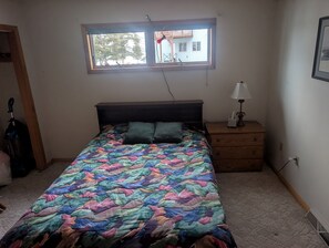 A bedroom with a bed, a nightstand, a window, and a door. - Eagle's Nest On The Water (Butternut)