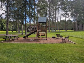 A playground with a slide, swing set, and picnic table. - Eagle's Nest On The Water (Butternut)