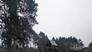 Un parc infantil amb tobogan i estructura per escalar, envoltat d'herba i arbres.