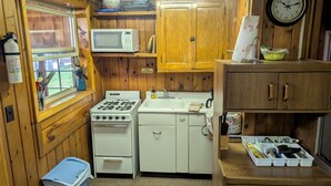Una cuina compacta amb fogó, microones, rentapelats i armaris.