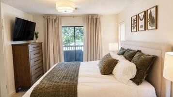 A hotel room with a bed, a television, a dresser, and a window with curtains.
