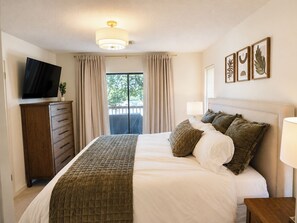 Ein Hotelzimmer mit einem Bett, einem Fernseher, einem Schminktisch und einem Fenster mit Vorhängen.