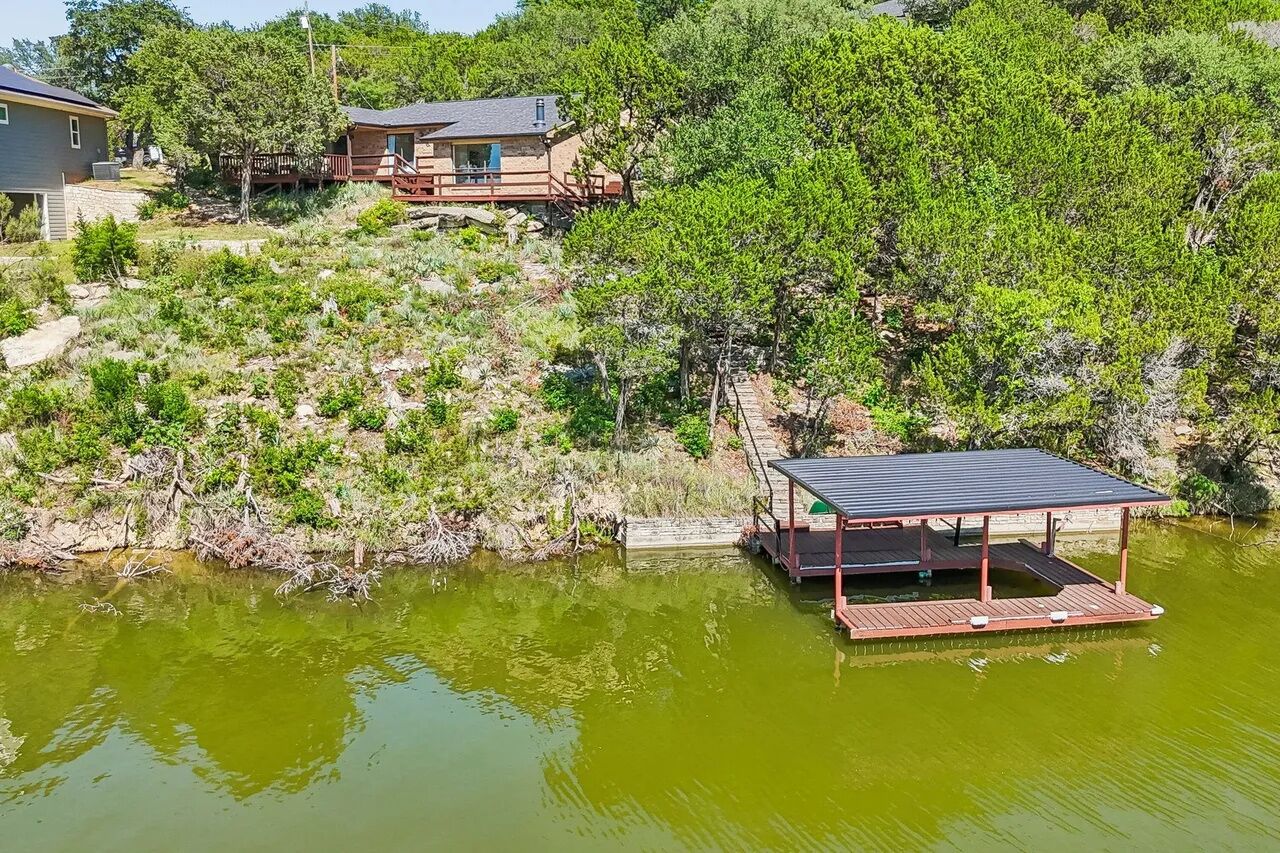A lakeside property with a wooden deck and a small pavilion.