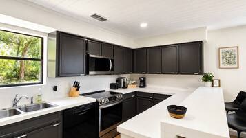 A modern kitchen with dark cabinets, a stainless steel microwave, a dishwasher, and a coffee maker.