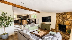 Ein geräumiges Wohnzimmer mit einem großen Sofa, einem Couchtisch und einem Kamin aus Stein.