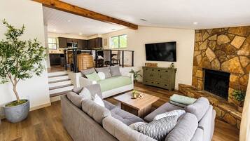 A spacious living room with a large sofa, a coffee table, and a stone fireplace.