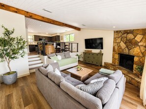 Ein geräumiges Wohnzimmer mit einem großen Sofa, einem Couchtisch und einem Kamin aus Stein.