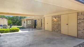 A covered outdoor area with a concrete floor, a brick wall, and a yellow door.