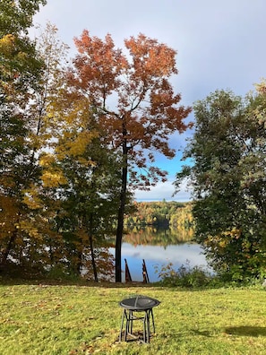 A grassy area with a table and chairs, a lake, and trees with autumn foliage. - Riverfront Retreat Near Trans-Ca Hwy 2 | Sleeps 8 (Upper Kent)