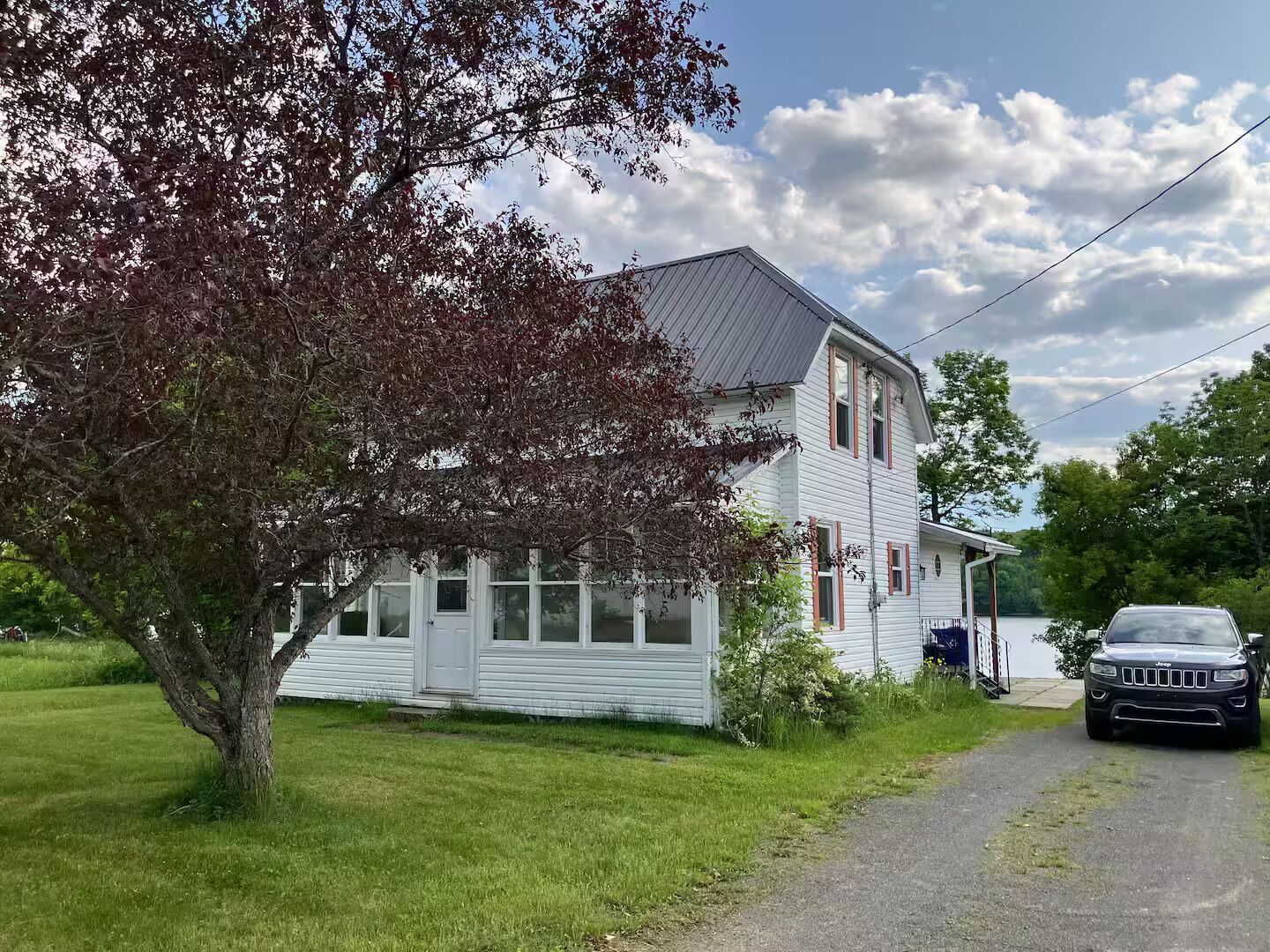A two-story house with a garage, a tree in front, and a driveway.