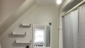Et badeværelse med toilet, håndvask, spejl og badeforhæng.