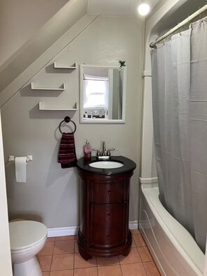 Un bagno con WC, lavandino, specchio e tenda da doccia.