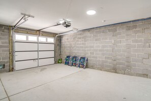 Eine Garage mit Betonboden, einer weißen Rolltür und einer Backsteinmauer.