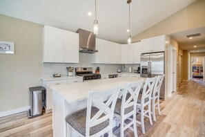 A modern kitchen with white cabinetry, a stainless steel refrigerator, and a central island with bar stools. - Fantastic 4-bedroom condo - Walk to the Beach! (Wildwood)
