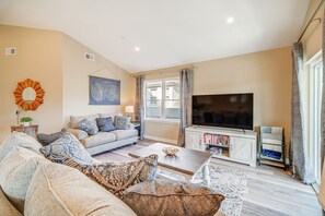 A living room with a sofa, coffee table, TV, and bookshelf. - Fantastic 4-bedroom condo - Walk to the Beach! (Wildwood)