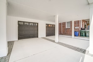 A garage with two dark grey doors, a white exterior wall, and a brick building in the background. - Fantastic 4-bedroom condo - Walk to the Beach! (Wildwood)