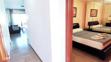 A hotel room with a bed, bedside table, and a mirror.