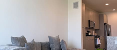 Una sala de estar moderna con un sofá seccional, una mesa de centro de vidrio y un tapete con diseño de mármol.
