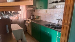 A kitchen with green cabinets, a stove, a sink, and a table with a towel. - Centrally Located, Fully Furnished Apartment with Support Services and Close to Everything! (Tarija)