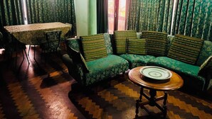 A room with a green patterned sofa, a round wooden table, and a dining table with chairs. - Centrally Located, Fully Furnished Apartment with Support Services and Close to Everything! (Tarija)