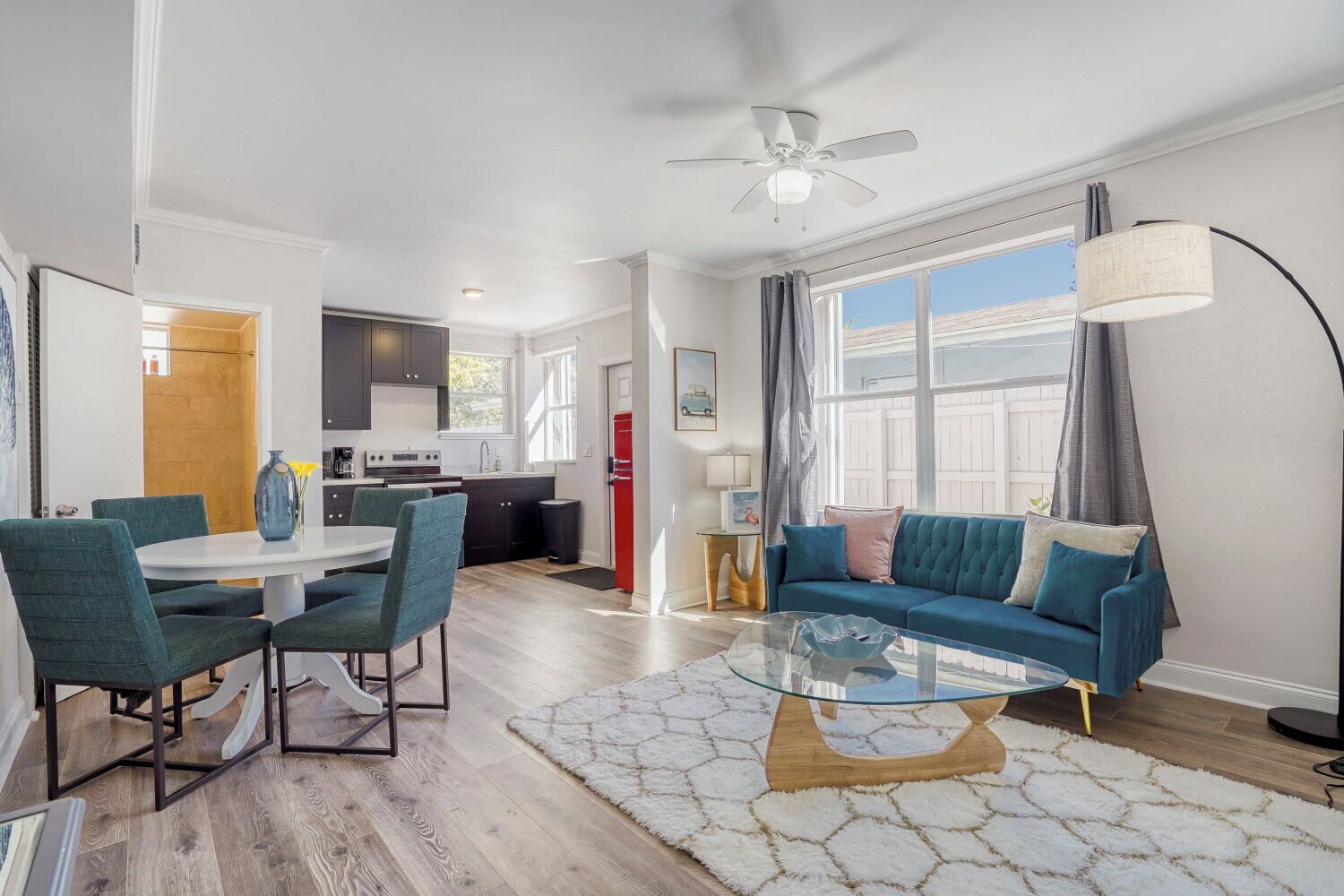 A modern living room with a sofa, a glass coffee table, and a dining area with chairs and a table.