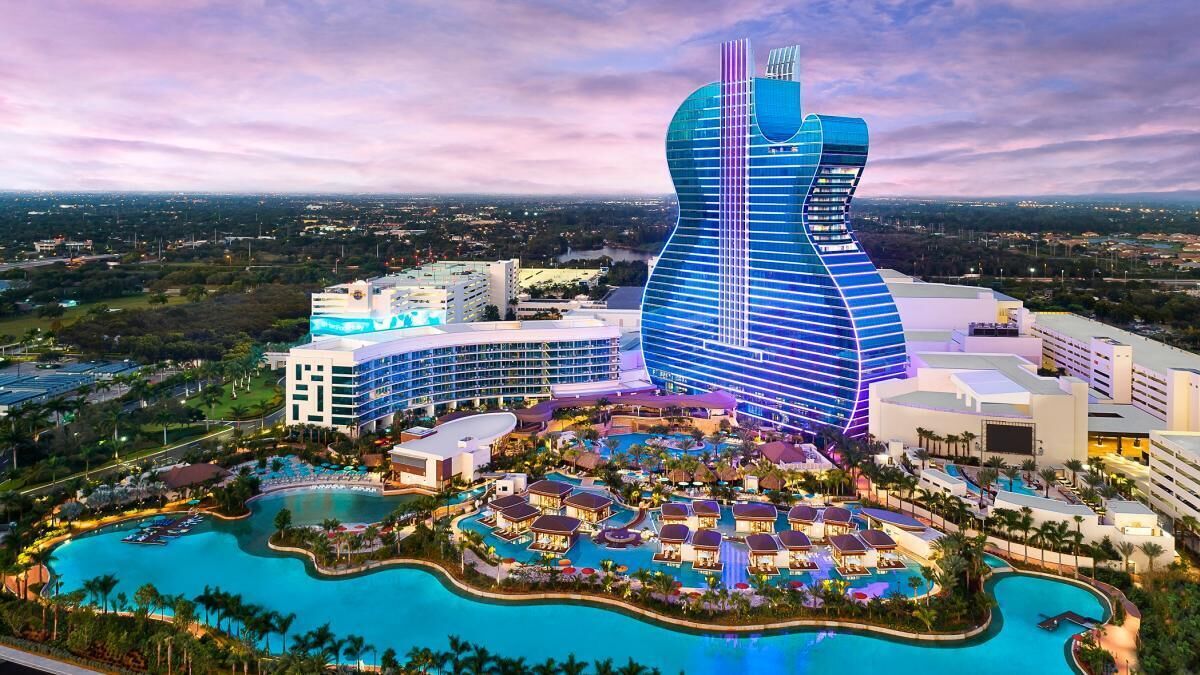 A resort with a large pool area, multiple buildings, and a distinctive guitar-shaped hotel.